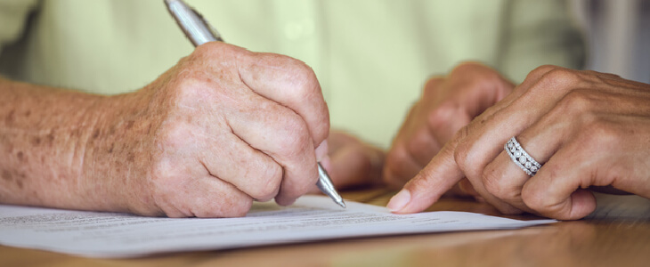 An elderly man signing and finalizing his will