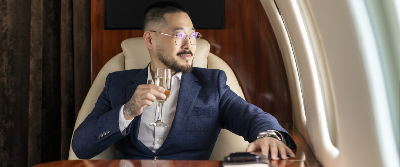 Rich man sitting on private jet drinking champagne