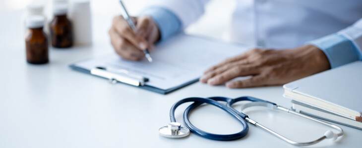 Doctor writing on a clipboard at a desk