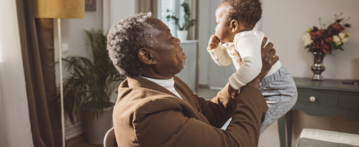 Proud Grandfather Cuddling Baby Grandson at family dinner party