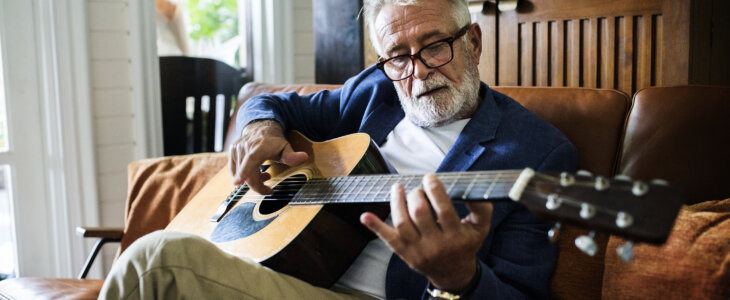 An elderly man is playing guitar