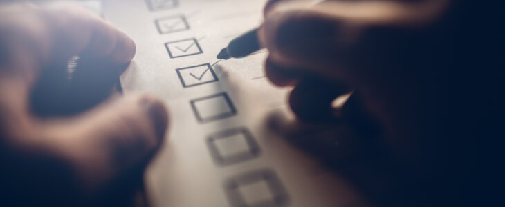 Close-up of businessmans hands filling a checklist