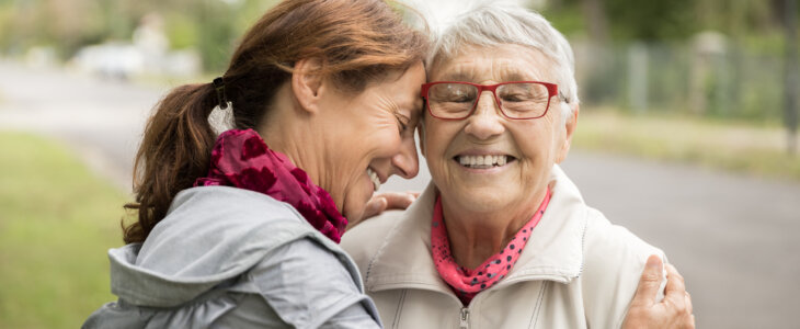 Happy senior woman and caregiver walking outdoors